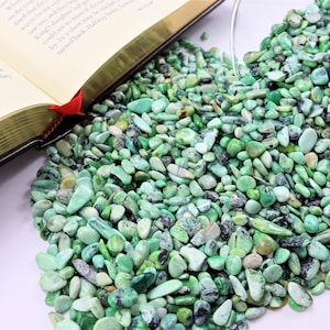 May include: A close-up of a pile of green and white variscite gemstone chips. The chips are various sizes and shapes, and some have a darker green color.