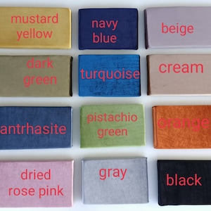 K&ouml;nnte beinhalten: Eine Sammlung rechteckiger Stoffmuster in verschiedenen Farben, darunter Senfgelb, Marineblau, Beige, Dunkelgr&uuml;n, T&uuml;rkis, Creme, Anthrazit, Pistaziengr&uuml;n, Orange, getrocknetes Rosarot, Grau und Schwarz. Jedes Muster hat einen roten Farbnamen.