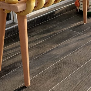 May include: A wooden bench with a yellow velvet cushion. The bench has four legs and is made of natural wood. The cushion is made of a soft, plush fabric.
