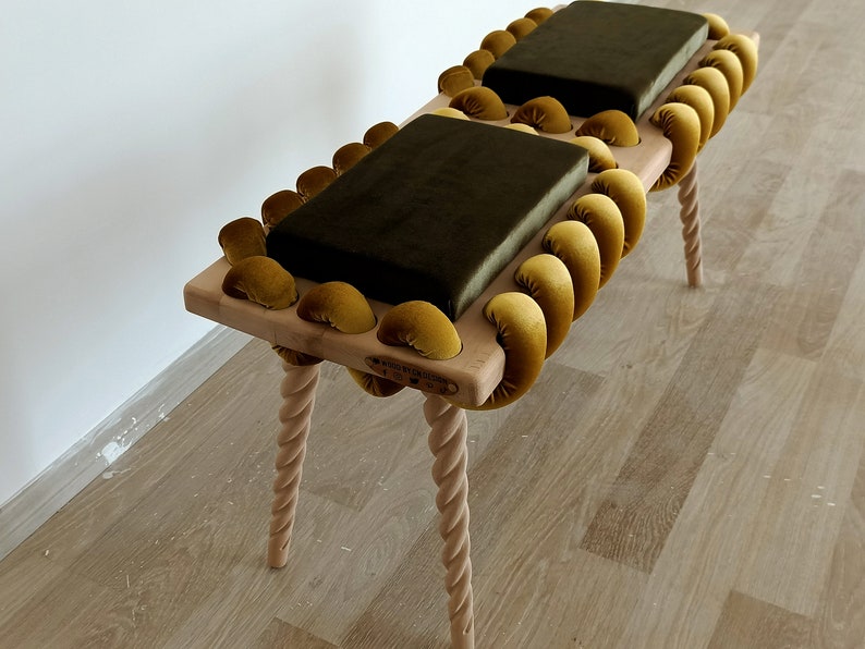 May include: A wooden bench with a unique design featuring a braided rope-like frame with gold velvet cushions. The bench has four twisted legs and a wooden top.