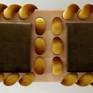 May include: A wooden bench with two cushioned seats. The seats are covered in dark green fabric and the edges are trimmed with a rope-like design in a bright yellow color.