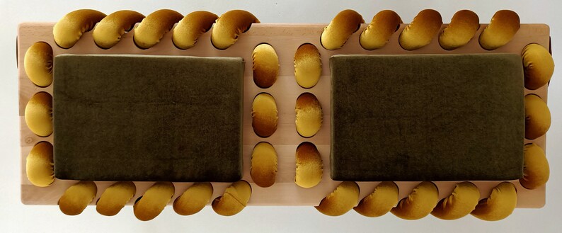 May include: A wooden bench with two cushioned seats. The seats are covered in dark green fabric and the edges are trimmed with a rope-like design in a bright yellow color.