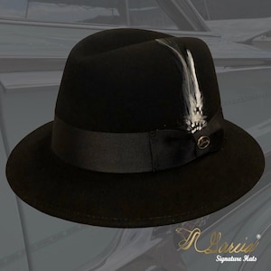 May include: A black fedora hat with a black ribbon and a white feather accent. The hat has a small gold pin with the word "Larisa" on it.