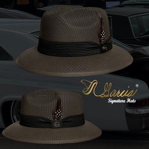 May include: A brown fedora hat with a black band and a small feather accent. The hat has a textured woven design and a signature logo on the side. The hat is displayed against a black background.