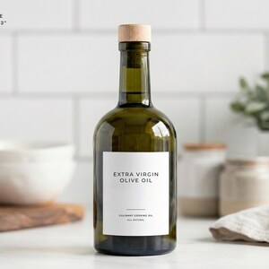 Op de afbeelding: Een groene glazen fles extra vierge olijfolie met een houten stop. Het etiket is wit met zwarte tekst "EXTRA VIRGIN OLIVE OIL". De labelgrootte is 6,35 cm x 7,62 cm. Culinaire bakolie, allemaal natuurlijk.