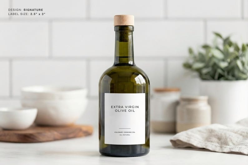 Op de afbeelding: Een groene glazen fles extra vierge olijfolie met een houten stop. Het etiket is wit met zwarte tekst "EXTRA VIRGIN OLIVE OIL". De labelgrootte is 6,35 cm x 7,62 cm. Culinaire bakolie, allemaal natuurlijk.