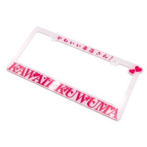 Op de afbeelding: Een roze plastic kentekenplaathouder met de tekst "Kawaii Kuwuma" en "かわいい車  がんば!" in roze letters. De houder heeft twee kleine roze hartjes in de rechterbovenhoek.