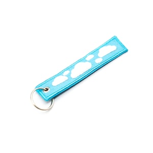 May include: A light blue key chain with a white cloud design and a silver key ring.