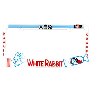 以下が含まれることがあります： 白いナンバープレートフレーム。赤い「White Rabbit」の文字と漫画のウサギが描かれています。フレーム上部には青いストライプと日本語の文字、側面には赤い「Kawaii」と「Kuwuma」の文字があります。