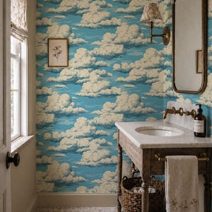 Peut inclure: Salle de bain avec papier peint représentant un ciel bleu et des nuages. La pièce comprend une coiffeuse en marbre avec une base en bois, un lavabo rond et un miroir vintage. Une impression botanique encadrée est accrochée au mur, et un panier en osier est sous l'évier.