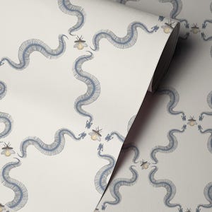 May include: Wallpaper roll with a repeating pattern of blue snake skeletons and yellow insects on a cream backdrop. The design has a whimsical, slightly macabre aesthetic, suitable for interior decoration.