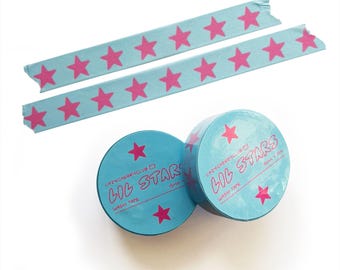 Peut inclure: Deux rouleaux de ruban adhésif washi bleu clair avec des motifs d'étoiles roses et deux bandes du même ruban. L'emballage porte le texte LAZYCHERRYCLUB, LIL STARS et 15mm x 10m imprimé en rose sur la surface bleu clair.