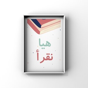 Könnte beinhalten: Ein weiß gerahmter Druck mit einer bunten Illustration von zwei übereinander gestapelten Büchern. Der Text "ما تقرأ" ist in arabischer Schrift in der Mitte des Drucks geschrieben.