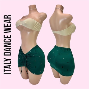 May include: A two-piece dance outfit featuring a beige strapless bandeau top and a dark green mini skirt with a drawstring front and scattered rhinestones. The text ITALY DANCE WEAR is printed vertically on the left side of the image.