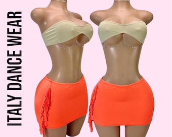 May include: Two mannequins display a beige strapless bandeau top with a delicate silver chain detail and a bright orange mini skirt featuring side fringe accents. The text ITALY DANCE WEAR is printed vertically in black on the left side.