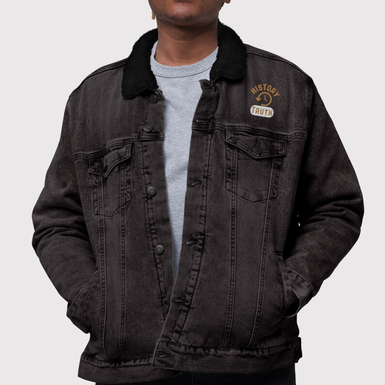 May include: A dark gray denim jacket with a black faux fur collar. The jacket has two chest pockets, two side pockets, and a button-up front. A patch on the upper chest reads "HISTORY TRUTH".