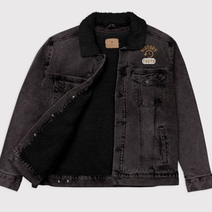 May include: A black denim jacket with a black sherpa lining and collar. The jacket has a button closure and two chest pockets. A patch on the chest reads "HISTORY TRUTH".