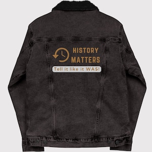 May include: A dark gray denim jacket with a black faux shearling collar. The back of the jacket features the text "HISTORY MATTERS" with a clock graphic and the phrase "Tell it like it WAS!" in a white box.