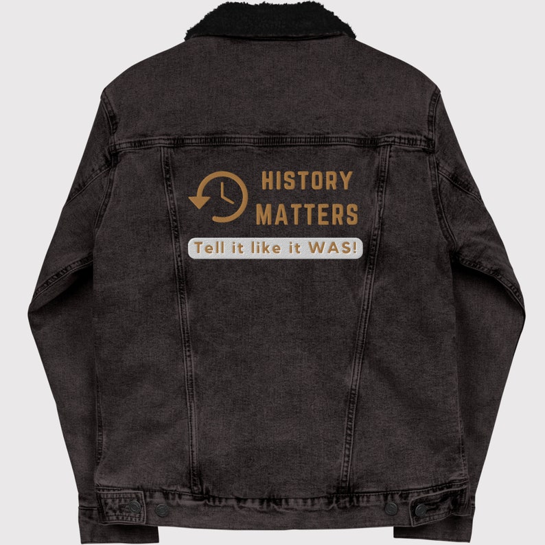 May include: A dark gray denim jacket with a black faux shearling collar. The back of the jacket features the text "HISTORY MATTERS" with a clock graphic and the phrase "Tell it like it WAS!" in a white box.