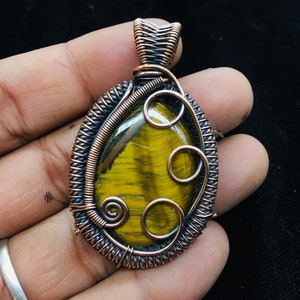 Peut inclure: Un pendentif en fil de cuivre enveloppé avec une pierre de œil de tigre jaune et brune.
