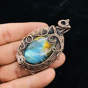 Peut inclure: Un pendentif en fil de cuivre enroulé avec une grande pierre de labradorite ovale aux reflets bleus, verts et dorés.
