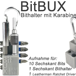 Op de afbeelding: Een grijze plastic bit houder met een karabijnhaak. De houder heeft slots voor 10 zeskant bits en een zeskant bit houder. De tekst op de houder luidt "BitBUX Bithalter mit Karabiner". De tekst onder de houder luidt "Aufnahme für: 10 Sechskant Bits 1 Sechskant Bithalter 1 Leatherman Ratchet Driver o.ä."