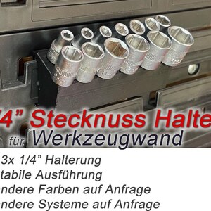 May include: A black 1/4 inch socket holder for a tool wall. The holder has 13 slots and is filled with sockets. The text "1/4" Stecknuss Halter für Werkzeugwand" is printed in red on a white background.