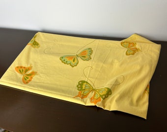 Pode incluir: Um lençol de tecido amarelo com um padrão de borboletas laranja, verdes e marrons.