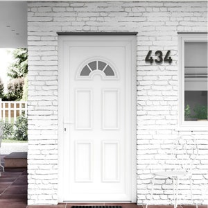 May include: A white front door with a half-circle window at the top and rectangular panels. The number "434" is displayed in black on the white brick wall. A white chair sits nearby.