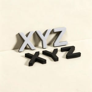 May include: A set of the letters X, Y, and Z in black and white. The white letters have a grey face and black trim. The black letters are solid. The letters are displayed on a neutral background.