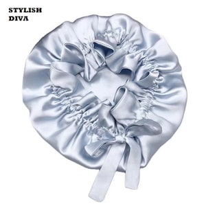 May include: A light blue satin bonnet with a ruffled design and a bow. The text "STYLISH DIVA" is in the upper left corner. The bonnet is designed to protect hair while sleeping.