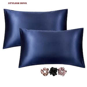 May include: Two navy blue satin pillowcases with a glossy sheen. The pillowcases are rectangular and have a smooth texture. Three satin scrunchies in shades of black, tan, and pink are at the bottom. The text "STYLISH DIVA" is at the top.