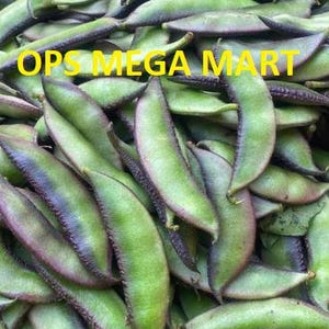 Könnte beinhalten: Nahaufnahme eines Haufens frischer, grüner Limabohnen mit violetten Rändern. Das Bild enthält den Text "OPS MEGA MART" in gelben Buchstaben. Die Bohnen haben eine leuchtend grüne Farbe.