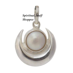 Puede incluir: Colgante plateado con una perla blanca engastada en un diseño de media luna. El colgante tiene un lazo para una cadena. El texto "Spiritual Stuff Shoppee" está impreso en la imagen.
