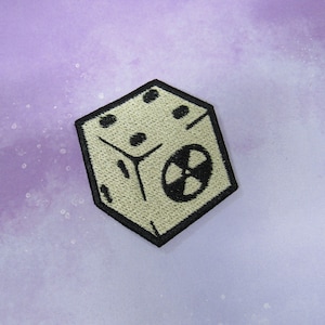 May include: A white embroidered patch shaped like a dice with a black radiation symbol on one side.