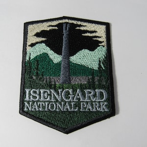 May include: A green and black embroidered patch with a gray tower and mountains. The text "Isengard National Park" is written in gray below the image.