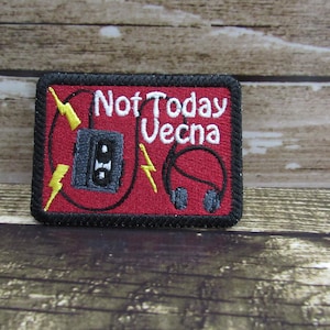 May include: Red embroidered patch with black stitching. The patch features a cassette tape, headphones, and lightning bolts. The text "Not Today Vecna" is embroidered in white.