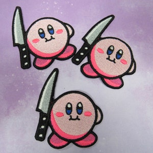 May include: Three pink and black embroidered patches of a cartoon character holding a knife. The character has large blue eyes and a small mouth.
