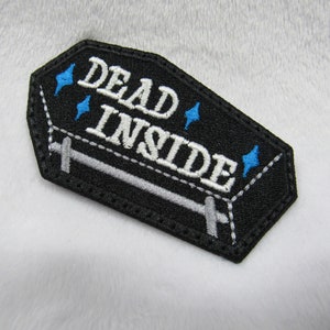 May include: Black embroidered patch shaped like a coffin with the text "DEAD INSIDE" in white and blue stars around the text.