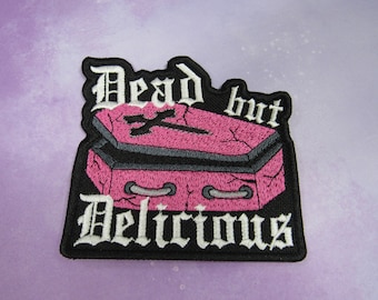 Puede incluir: Parche bordado en blanco y negro con un ataúd rosa y el texto "Dead but Delicious".