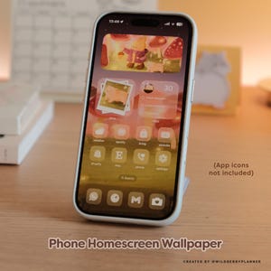 May include: A smartphone displaying a custom homescreen wallpaper with a whimsical forest scene, featuring a cartoon character and mushrooms. The phone is in a white case and is propped up on a stand. Text on the screen includes app icons and the words "Phone Homescreen Wallpaper".