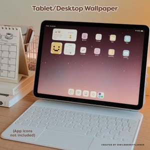 May include: A tablet with a white keyboard case displays a desktop wallpaper with app icons. The screen shows a pink and purple gradient background. A small calendar and other stationery items are visible in the background. Text on the screen says "Tablet/Desktop Wallpaper".