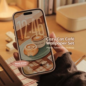 Könnte beinhalten: Ein Smartphone mit einem digitalen Hintergrundbild-Set namens Cozy Cat Café Wallpaper Set für Telefon, Tablet und Desktop. Der Bildschirm zeigt eine handgezeichnete Illustration einer Kaffeetasse und einer Zimtschnecke, mit dem Text Hand-drawn by @wildberryplanner.