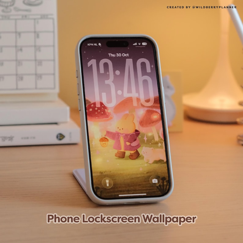 May include: A smartphone with a light blue case displays a whimsical phone lockscreen wallpaper featuring a cartoon bunny in a pink coat, holding a lantern, with mushroom illustrations. The time is 13:46. Text at the bottom reads "Phone Lockscreen Wallpaper."