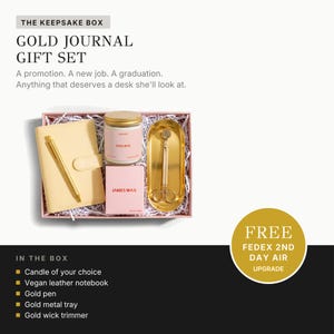 a gift set from James wax, including a gold journal, a candle, a pen, a leather notebook, a gold pen, a gold metal tray, and a gold wick trimmer. The gift set is presented in a box, and there is a free upgrade offer for the box.