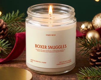 May include: A clear glass jar candle with a lit wick and white wax. The label reads JAMES WAX, BOXER SNUGGLES, Infused with wag-worthy joy, cuddle power, plenty of treats, and the sweet essence of a forever friend, SCENT 03, WHITE TEA + JASMINE, 100% SOY WAX.