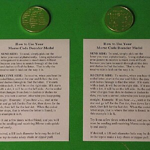 May include: Two white cards with instructions on how to use a Morse code decoder medal. The cards are on a green background. The medal is a gold-colored disc with a star in the center and dots and dashes around the star. The text on the cards explains how to send and receive Morse code using the medal. The text also mentions that a 1/8 inch diameter hole can be drilled in the top of the medal to make a key chain or zipper pull.