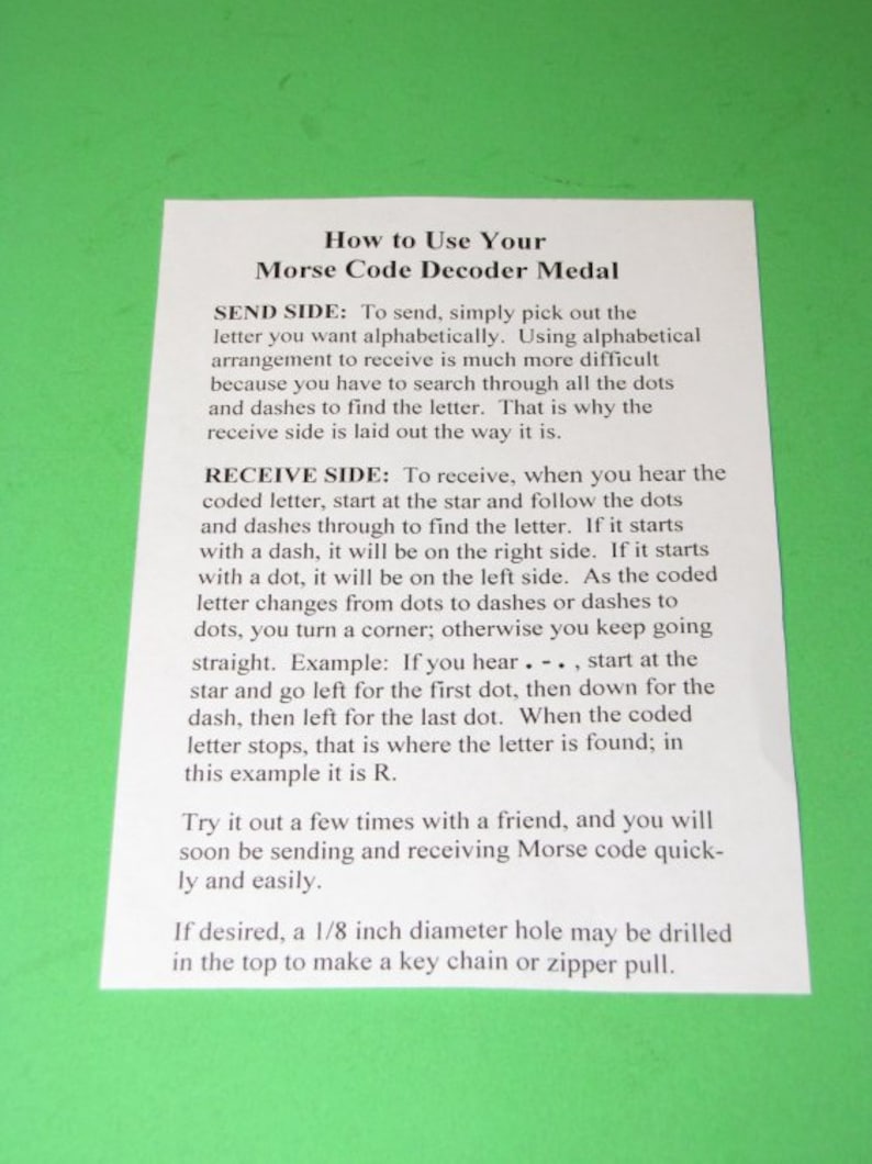 May include: A white sheet of paper with black text explaining how to use a Morse code decoder medal. The text includes instructions for sending and receiving Morse code, as well as an example of how to decode a letter.