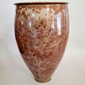 May include: A large, brown ceramic vase with a textured, bubble-like glaze. The vase has a wide mouth and a rounded base.