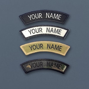 Op de afbeelding: Vier geborduurde patches met de tekst "YOUR NAME" in zwart, wit, bruin en camouflagekleuren. De patches zijn gebogen en hebben een gestikte rand.